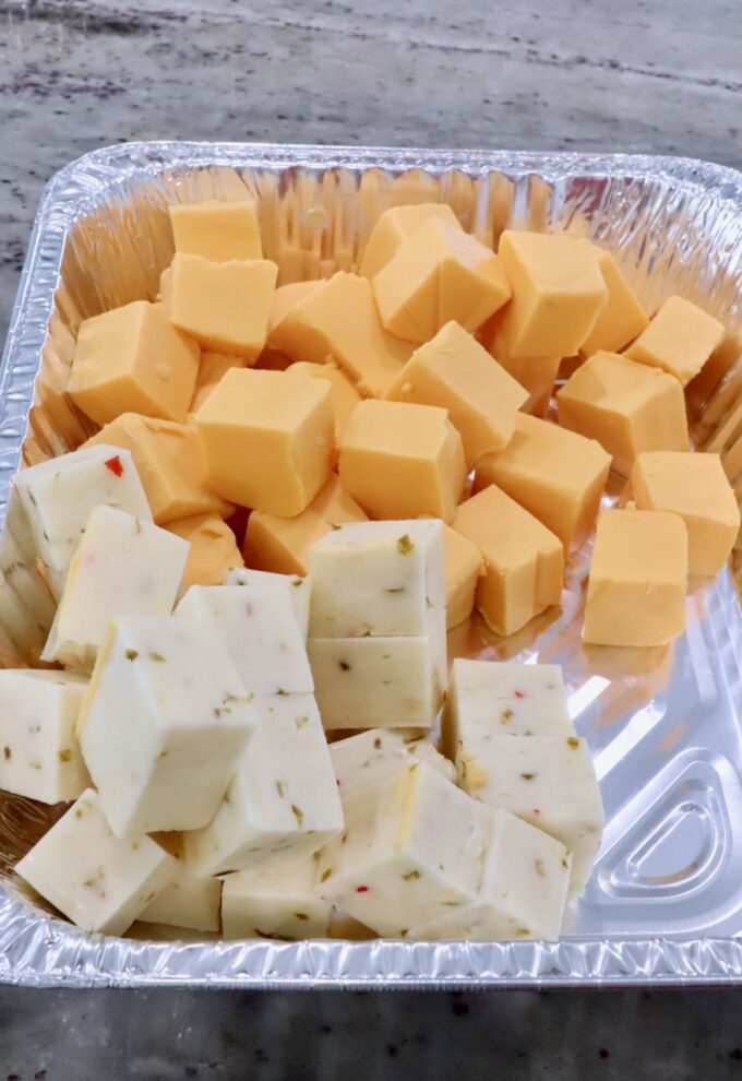 cubes of Velveeta cheese and pepper jack cheese in an aluminum foil pan
