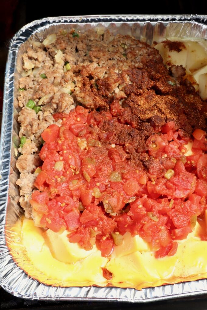 melted cheese, cooked, crumbled sausage, diced tomatoes and chili seasoning in an aluminum pan on a smoker