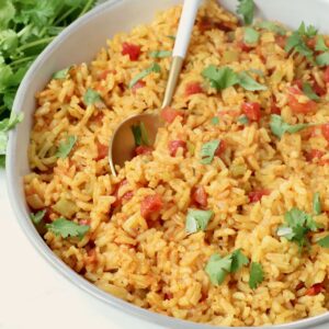 yellow rice in a bowl with a spoon and fresh cilantro