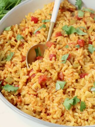 yellow rice in a bowl with a spoon and fresh cilantro
