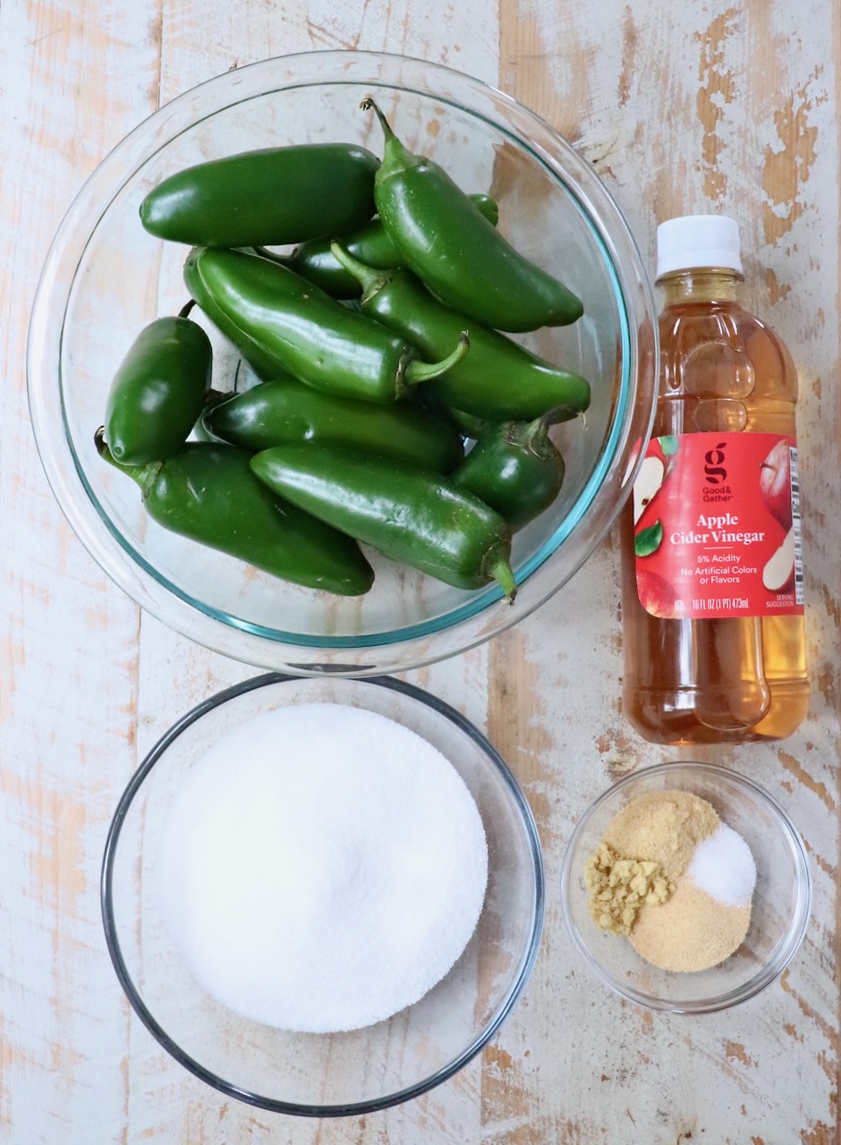 ingredients for candied jalapenos on a white wood board