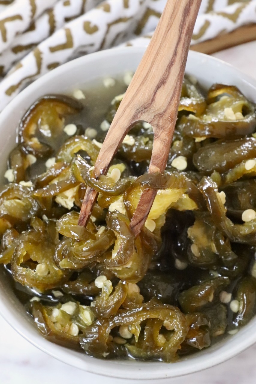 candied jalapenos in a bowl with a wooden fork
