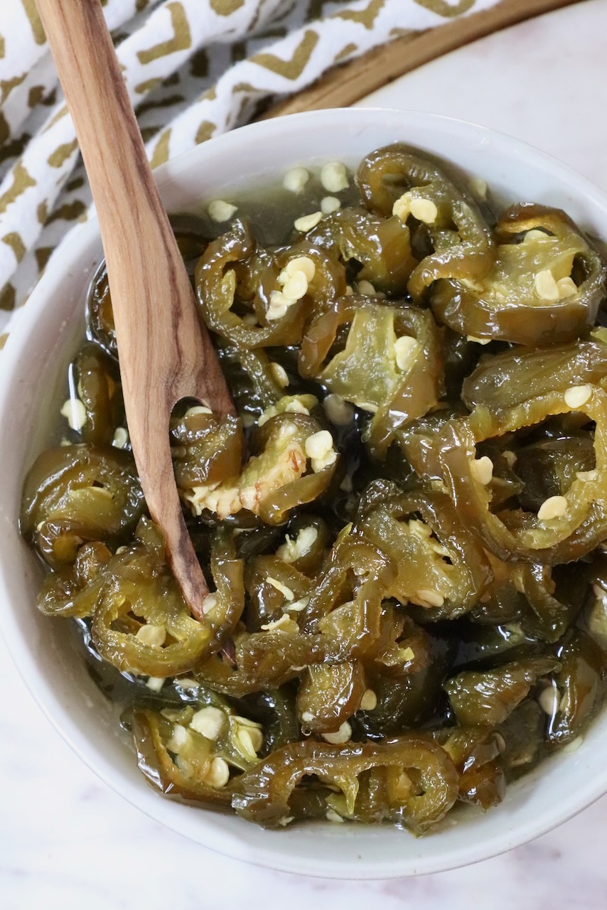 candied jalapenos in a bowl with a wooden fork