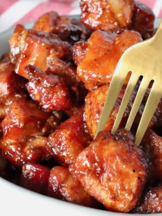 pork belly burnt ends in a bowl with a fork in one piece of pork belly