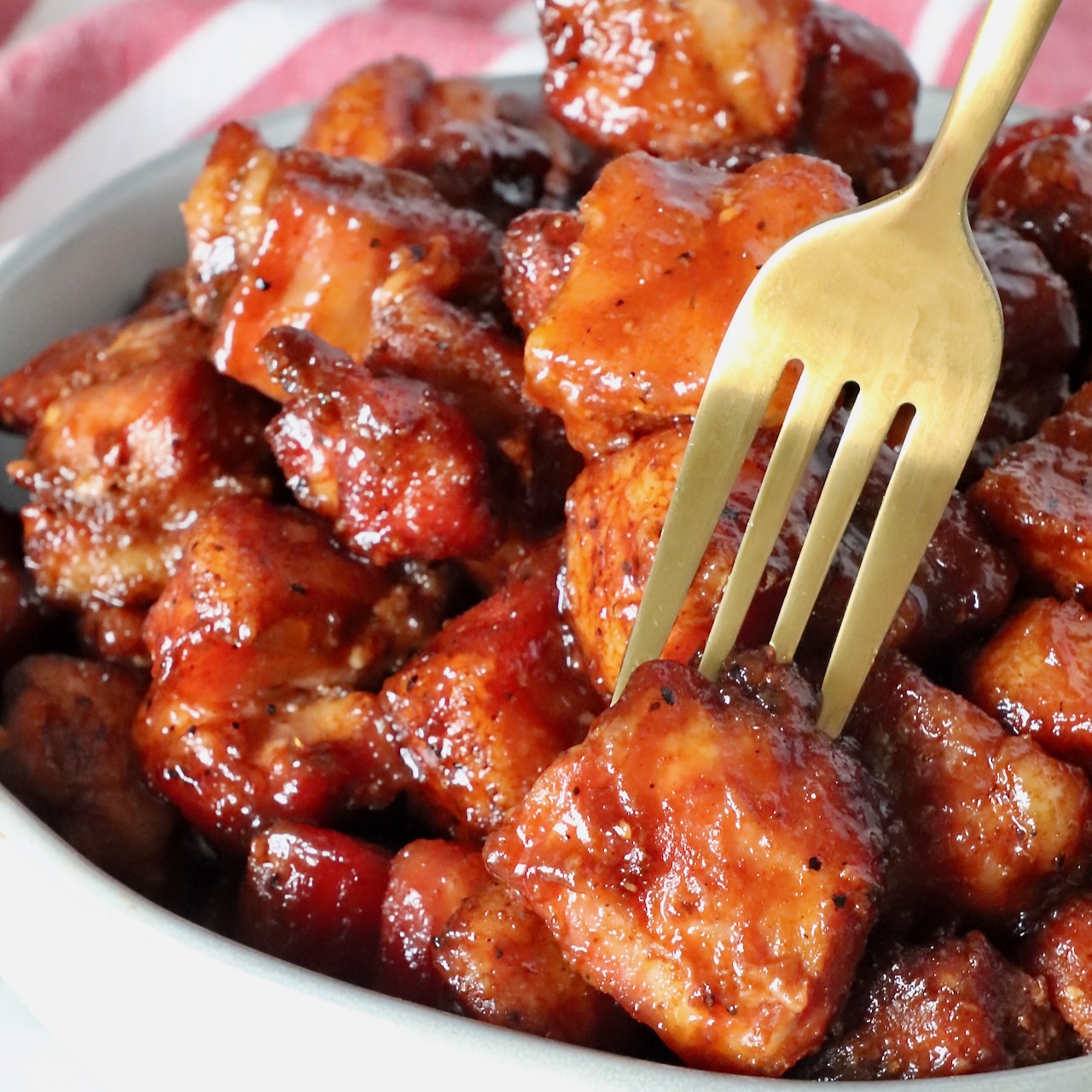 pork belly burnt ends in a bowl with a fork in one piece of pork belly