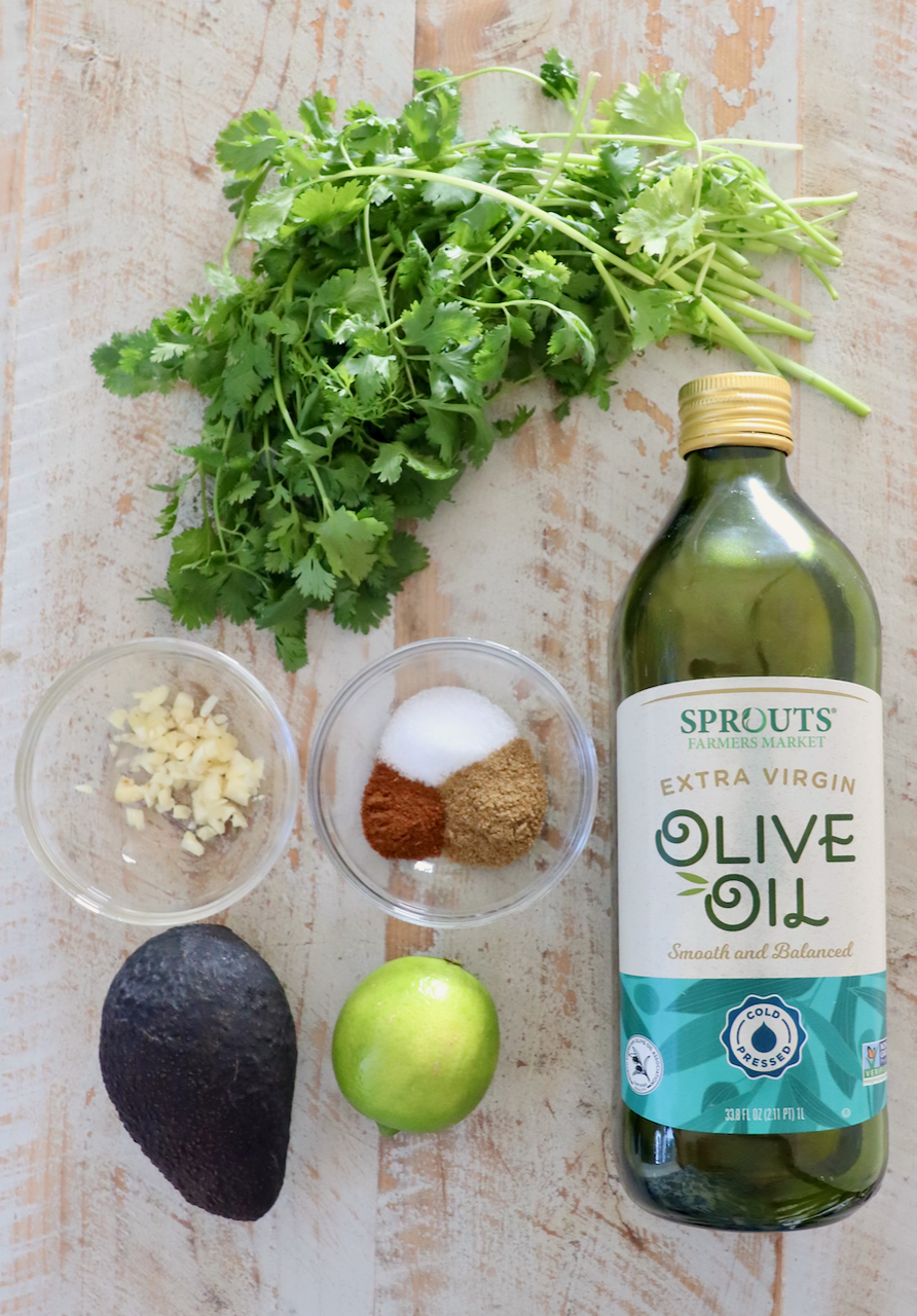 ingredients for avocado lime dressing on a white wood board