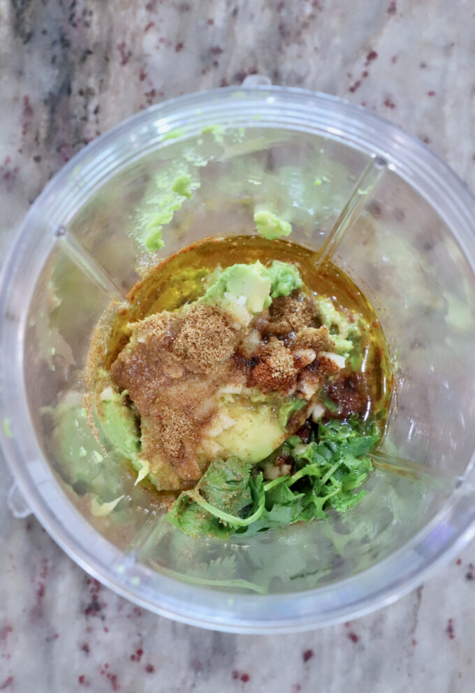 avocado, lime juice, cilantro and spices in a plastic blender cup
