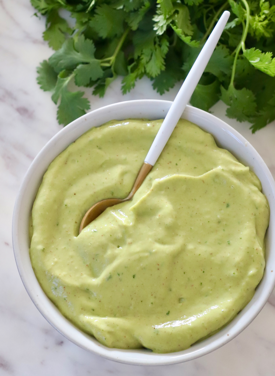 avocado dressing in a bowl with a spoon with fresh cilantro on the side