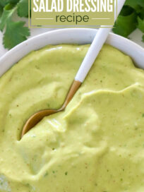 Bowl of creamy avocado lime salad dressing with a spoon. Fresh cilantro in the background. Text overlay reads: "5 Minute Avocado Lime Salad Dressing Recipe."