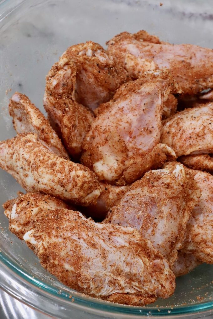seasoned raw chicken wings in a glass bowl