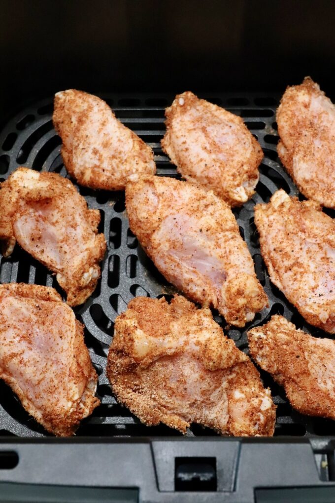 seasoned raw chicken wings in an air fryer basket