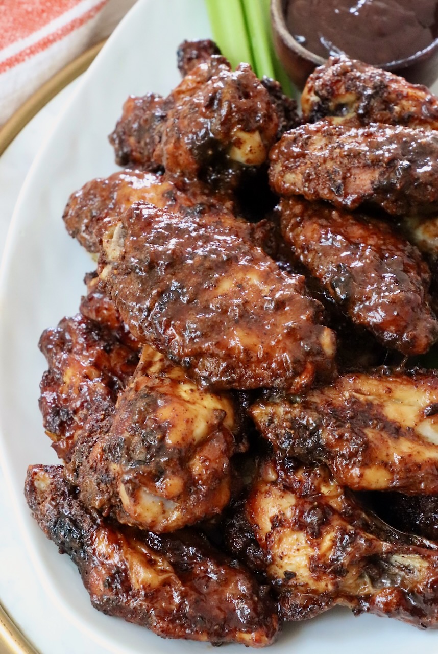 cooked chicken wings tossed in sauce stacked up on a plate