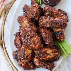 cooked chicken wings tossed in bbq sauce piled up on a plate