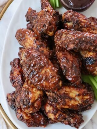 cooked chicken wings tossed in bbq sauce piled up on a plate