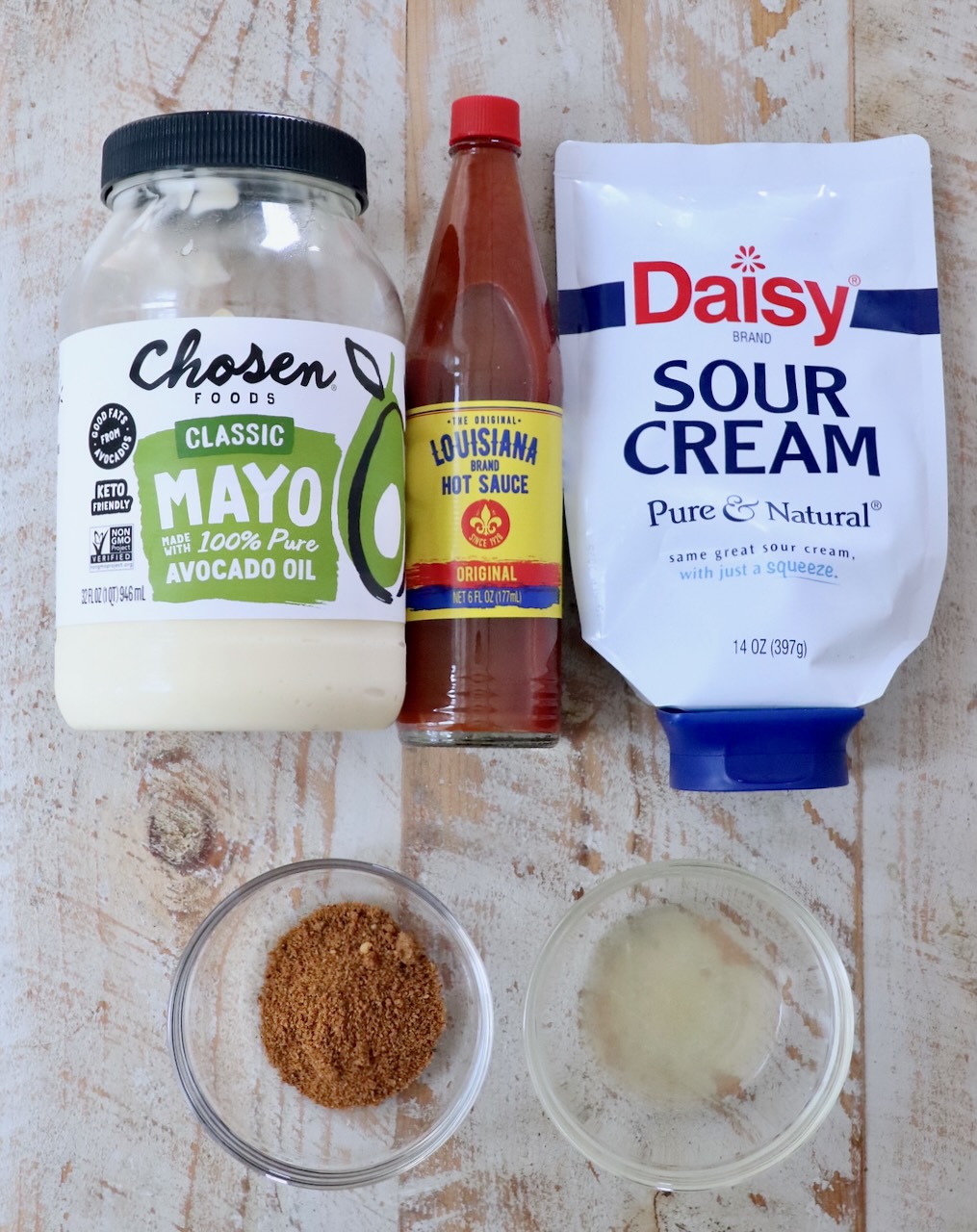ingredients for creamy cajun sauce on a white wood board