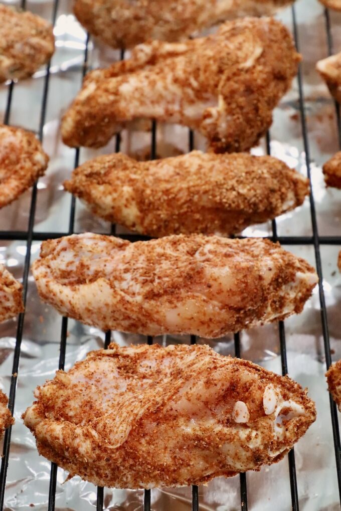 seasoned raw chicken wings on a wire rack on top of a baking sheet