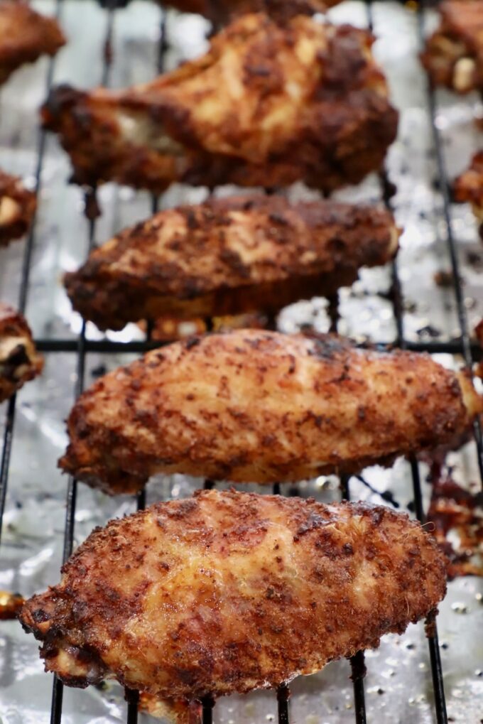 cooked, seasoned chicken wings on a wire rack on top of a baking sheet
