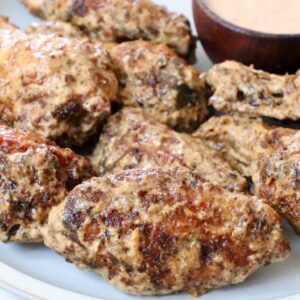 cooked chicken wings tossed in a creamy sauce on a plate
