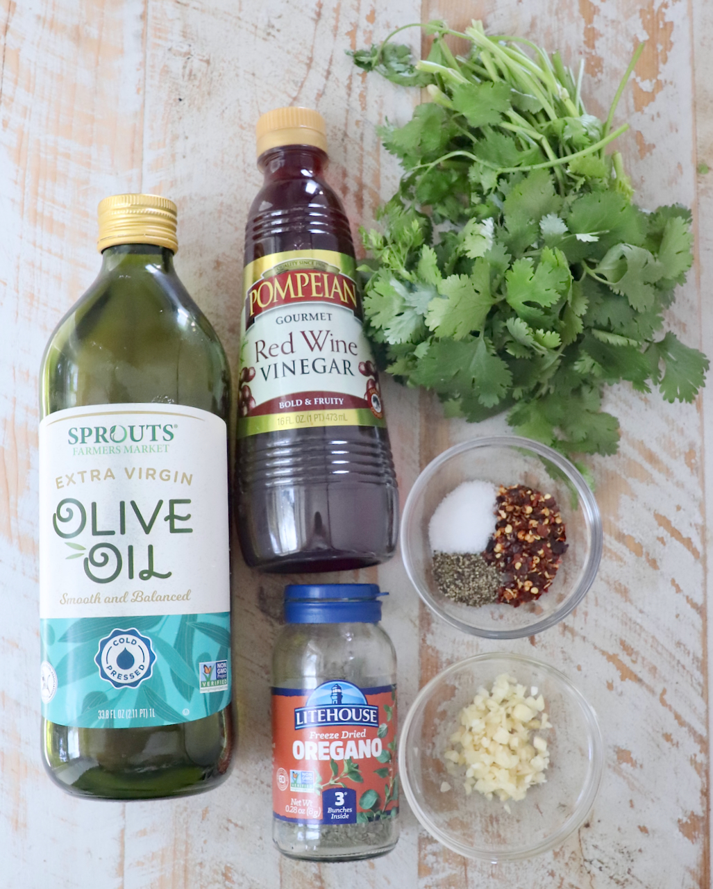 ingredients for cilantro chimichurri sauce on a white wood board