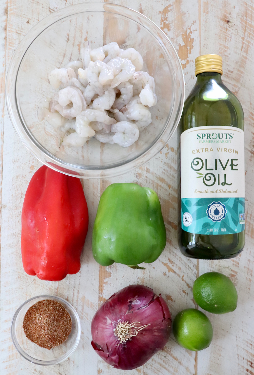 ingredients for shrimp fajitas on a white wood board