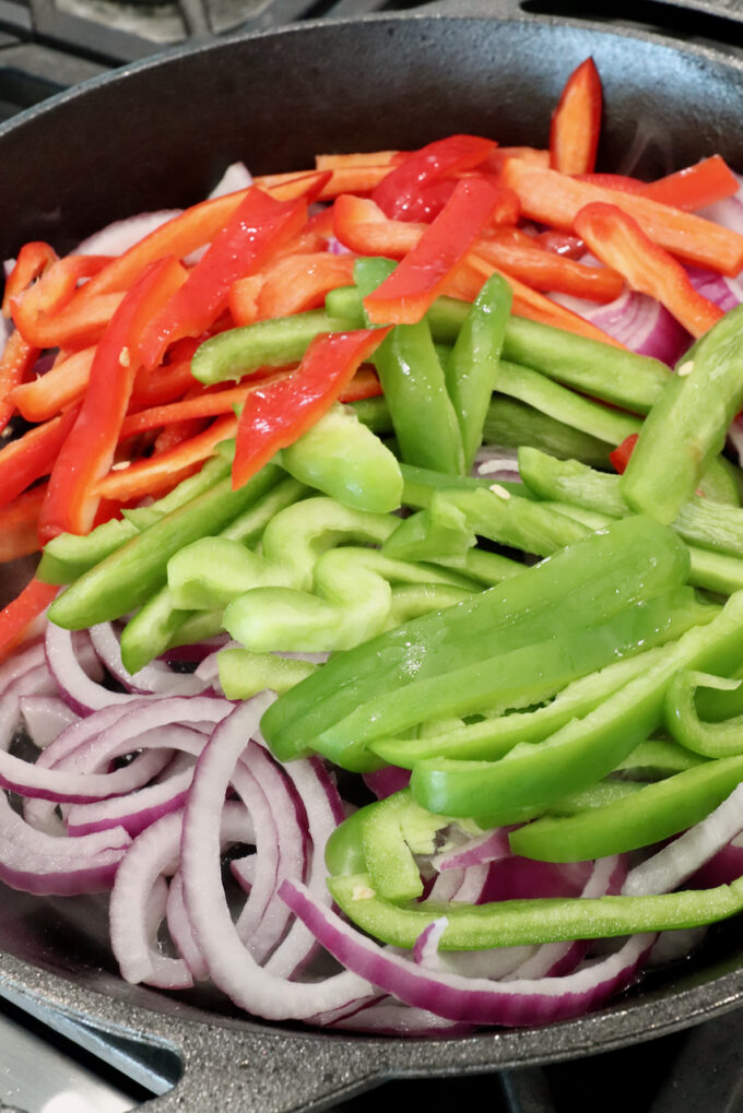 sliced bell peppers and onions in a skillet