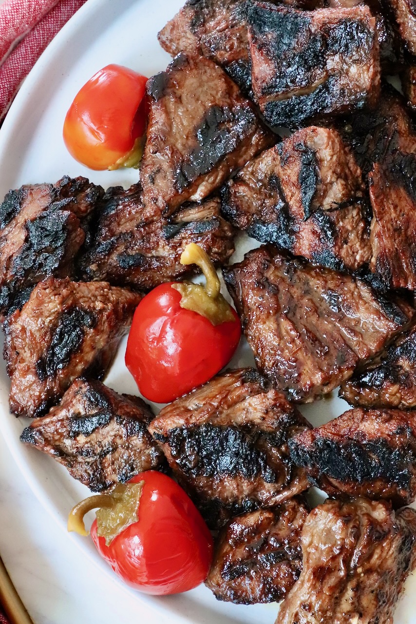 grilled steak tips on a plate with cherry peppers