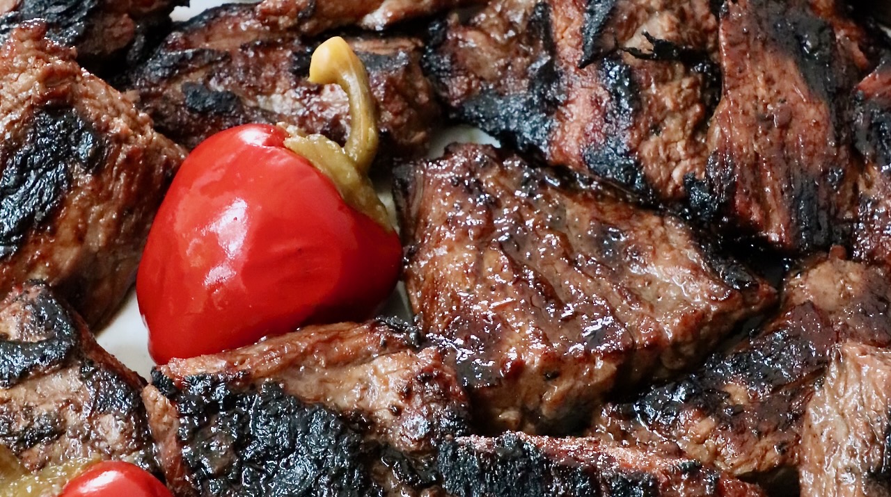 grilled steak tips on a plate with cherry peppers