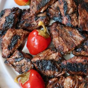 grilled steak tips on a plate with cherry peppers