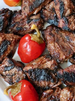 grilled steak tips on a plate with cherry peppers