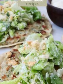 Close-up of chicken Caesar smash tacos on a plate. The tacos are topped with lettuce, croutons, and dressing. Text overlay promotes a 4-ingredient recipe.
