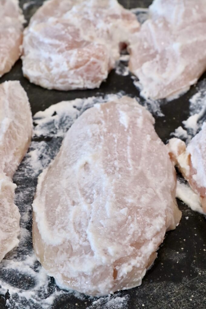 raw chicken breasts covered in a garlic spread on a cutting board