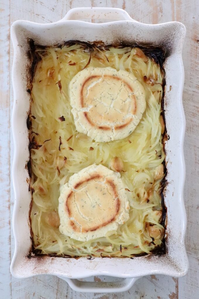 baked rounds of boursin cheese and caramelized onions in a white casserole dish