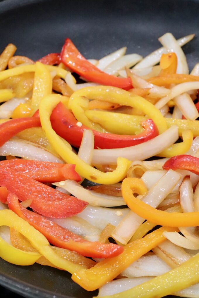 cooked, sliced peppers and onions in a skillet