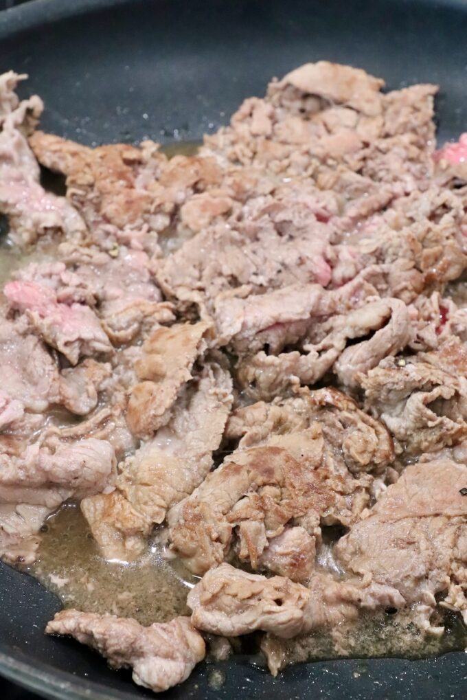 thinly sliced cooked steak in a skillet