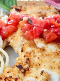 Close-up of a breaded chicken fillet topped with tomato bruschetta, accompanied by pasta and a basil leaf on a plate. Text overlay reads "5 Ingredient Trader Joe's Bruschetta Chicken Recipe."