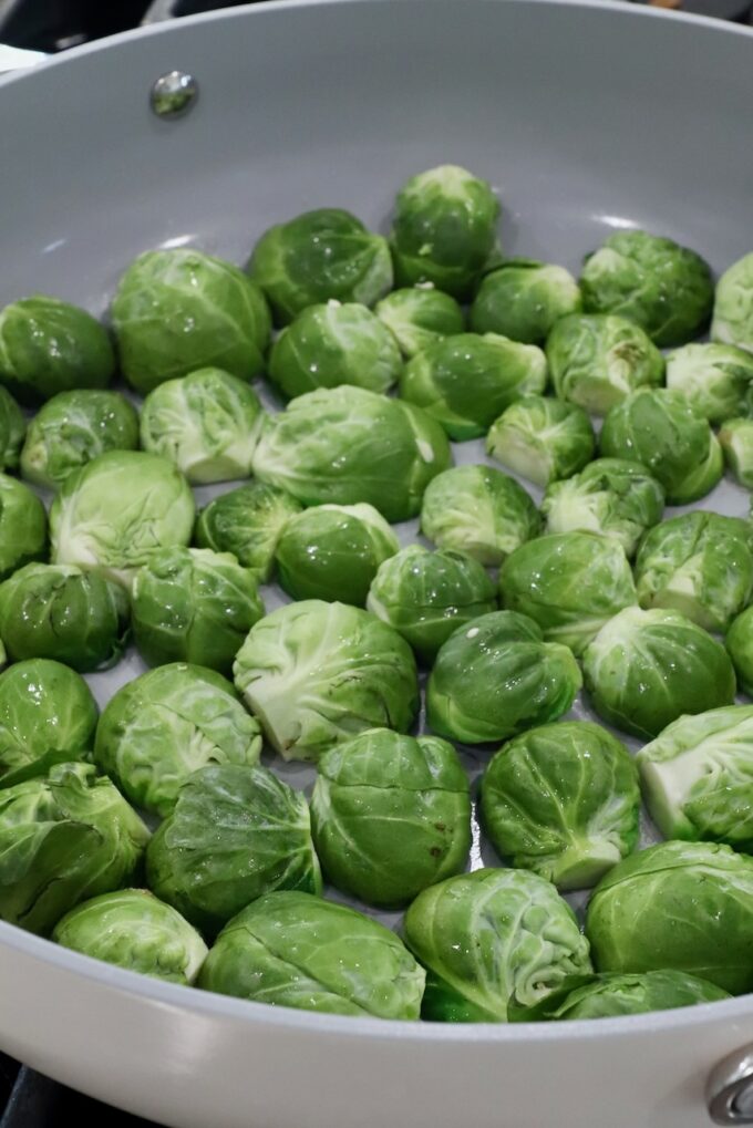 Fresh green Brussels sprouts evenly spread in a light-colored frying pan