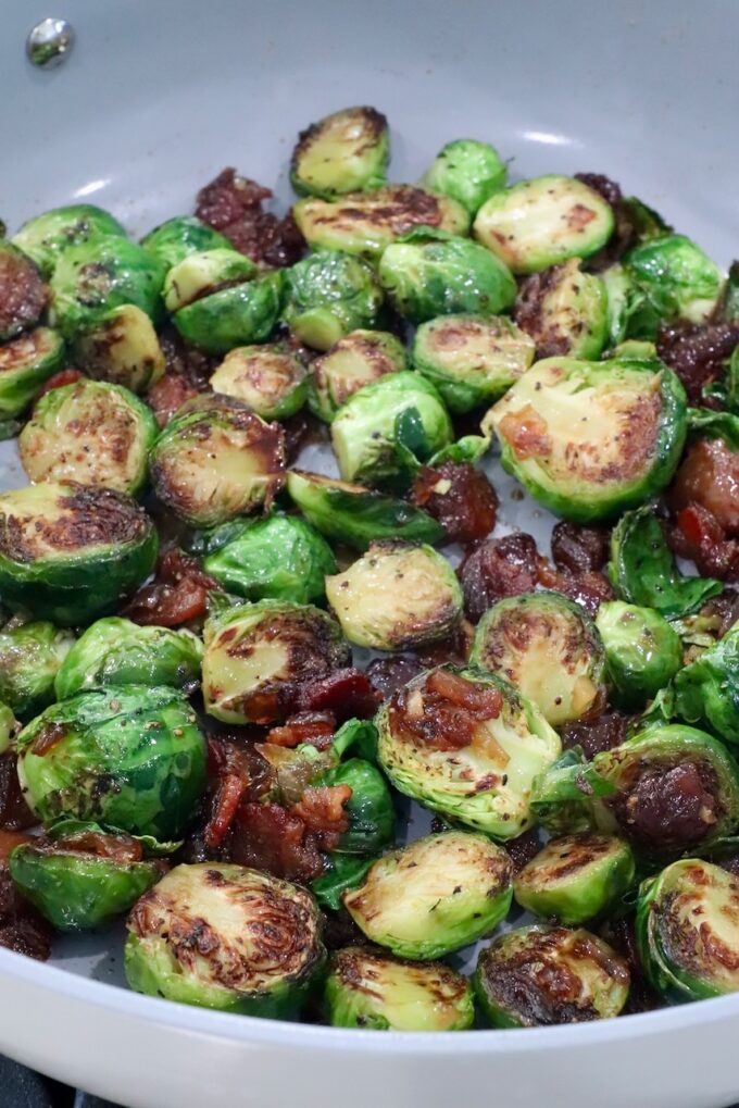 Caramelized Brussels sprouts with crispy, browned edges, mixed with bacon jam in a skillet