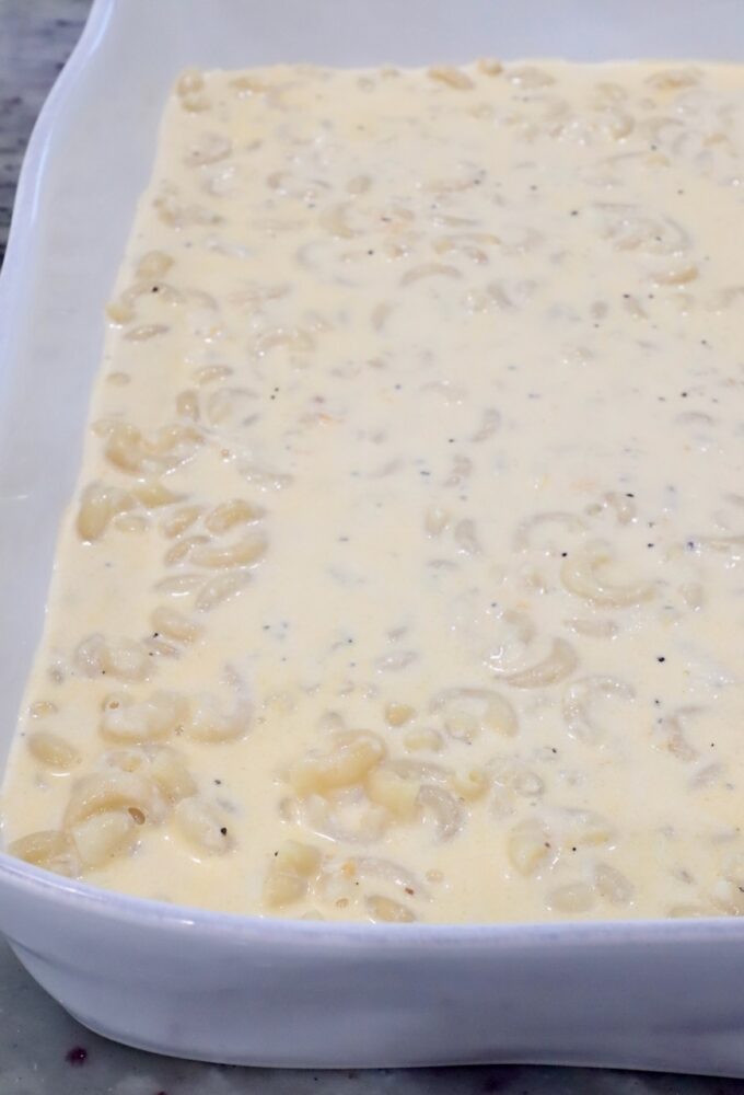A white baking dish filled with macaroni in a creamy, pepper-speckled cheese sauce