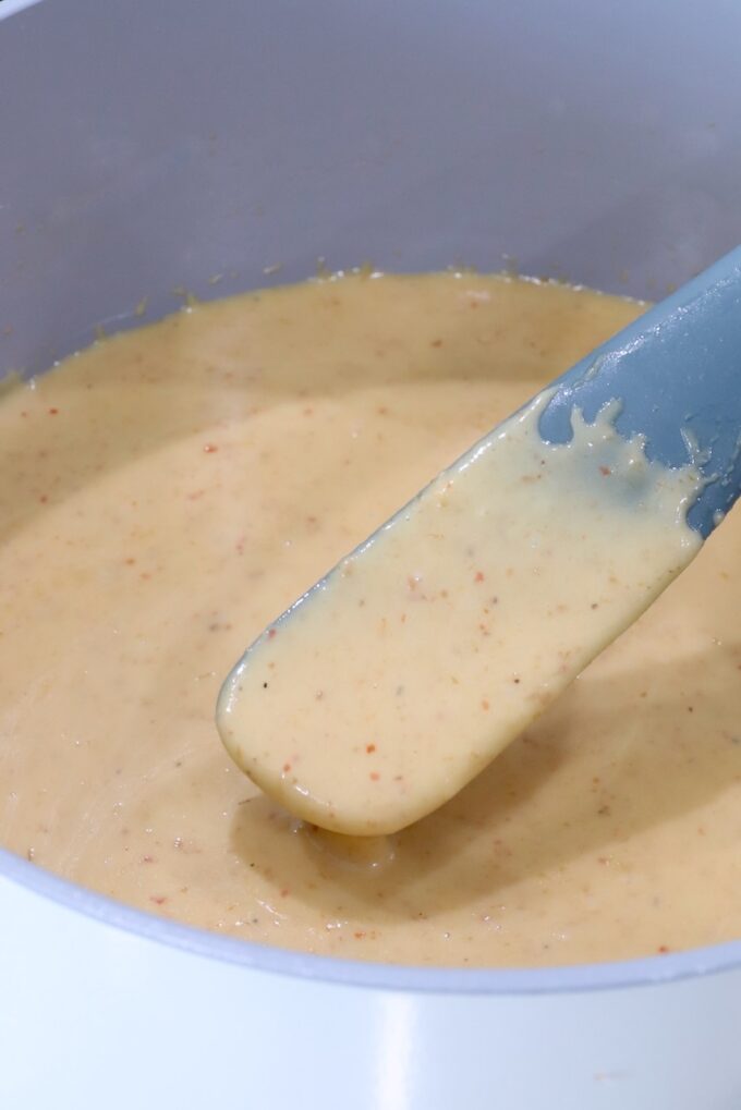 creamy queso in a pot with a grey spatula