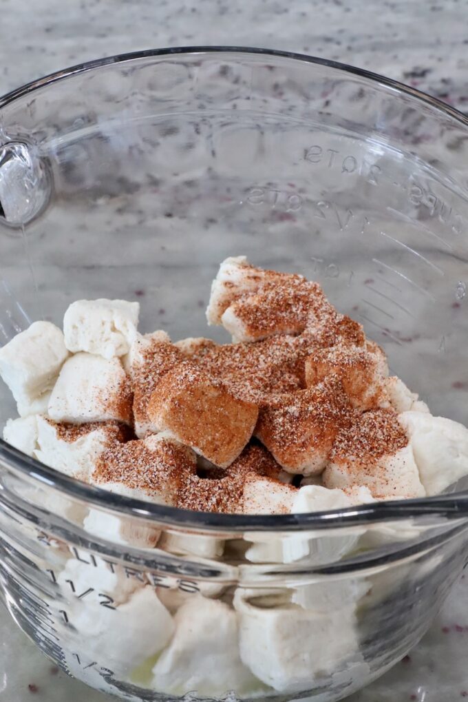 diced biscuits covered in seasoning in a glass bowl