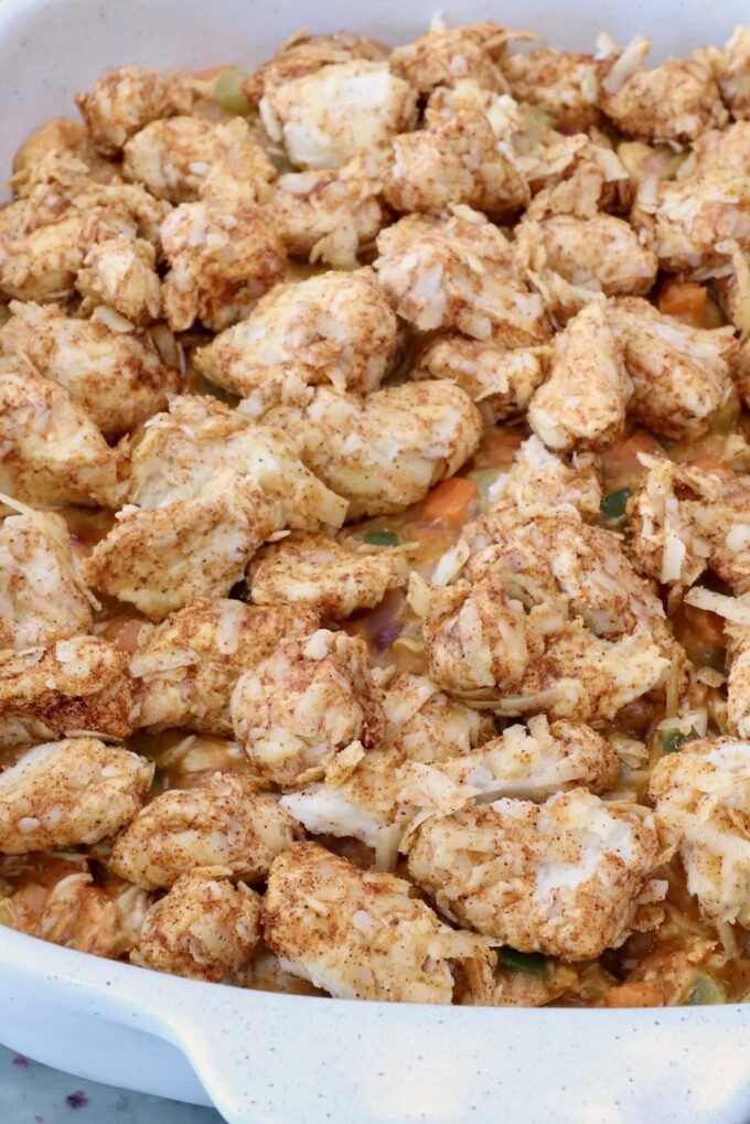 seasoned cubes of biscuit dough on top of pot pie filling in a baking dish