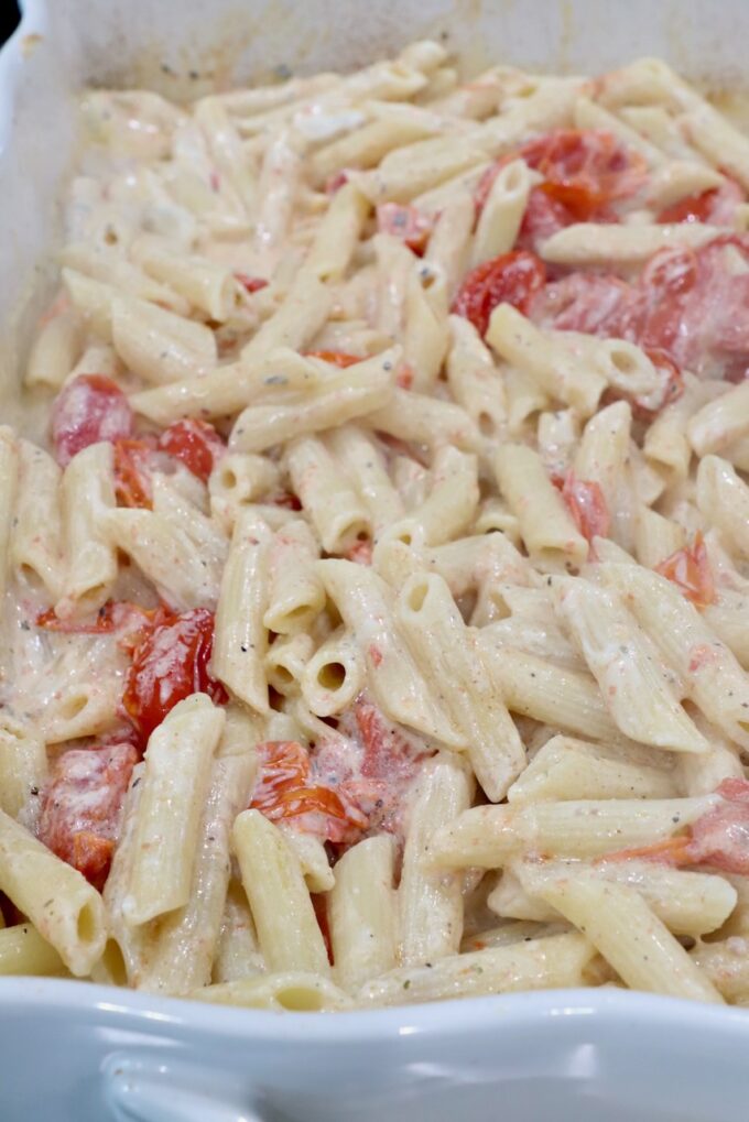 penne pasta in a creamy sauce with cherry tomatoes in a baking dish