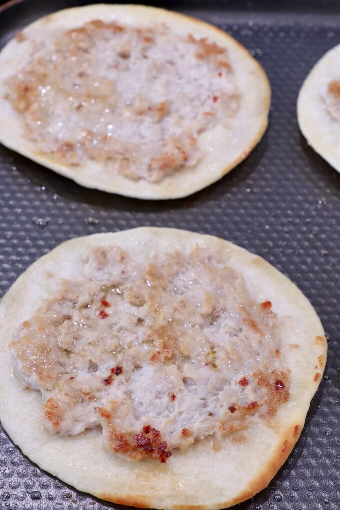 smash tacos on a griddle with the meat facing up