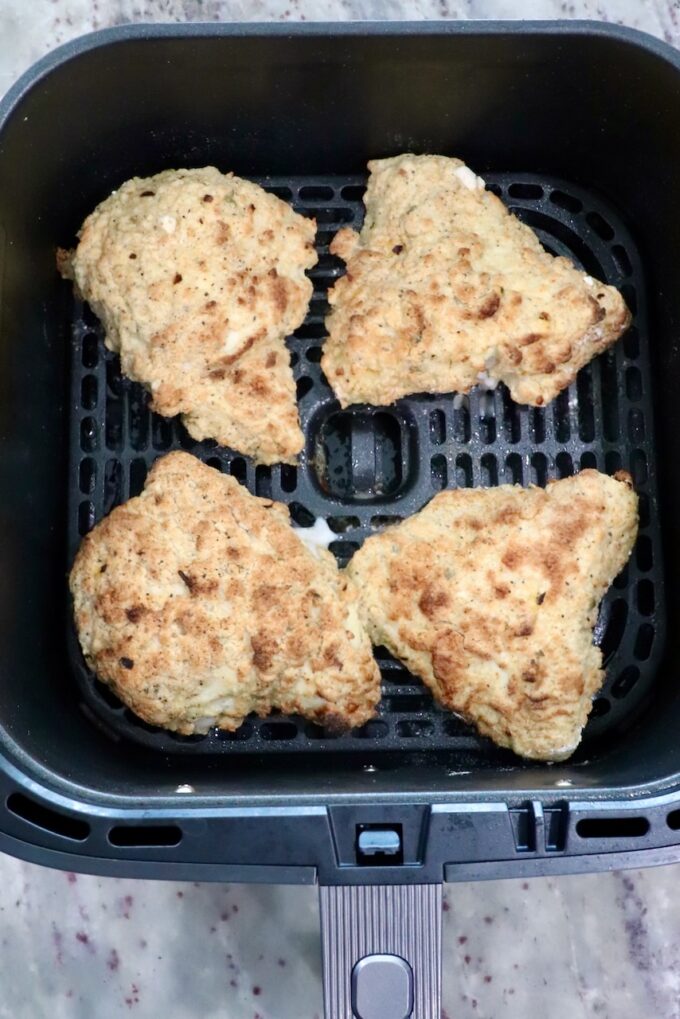 cooked pieces of chicken in an air fryer basket