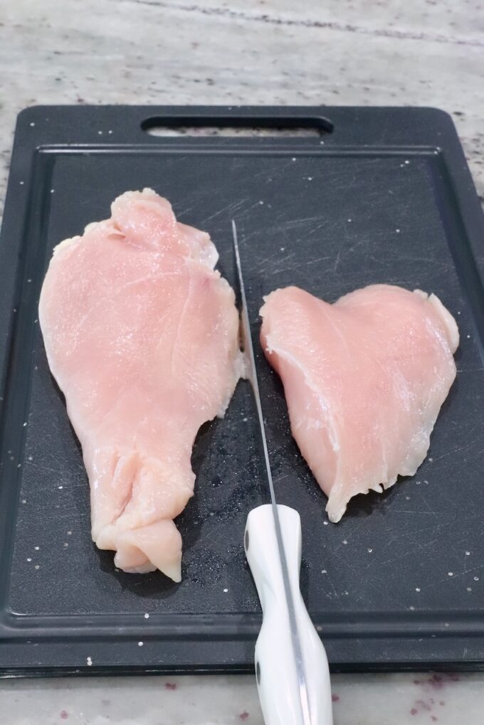chicken breast sliced in half on a cutting board