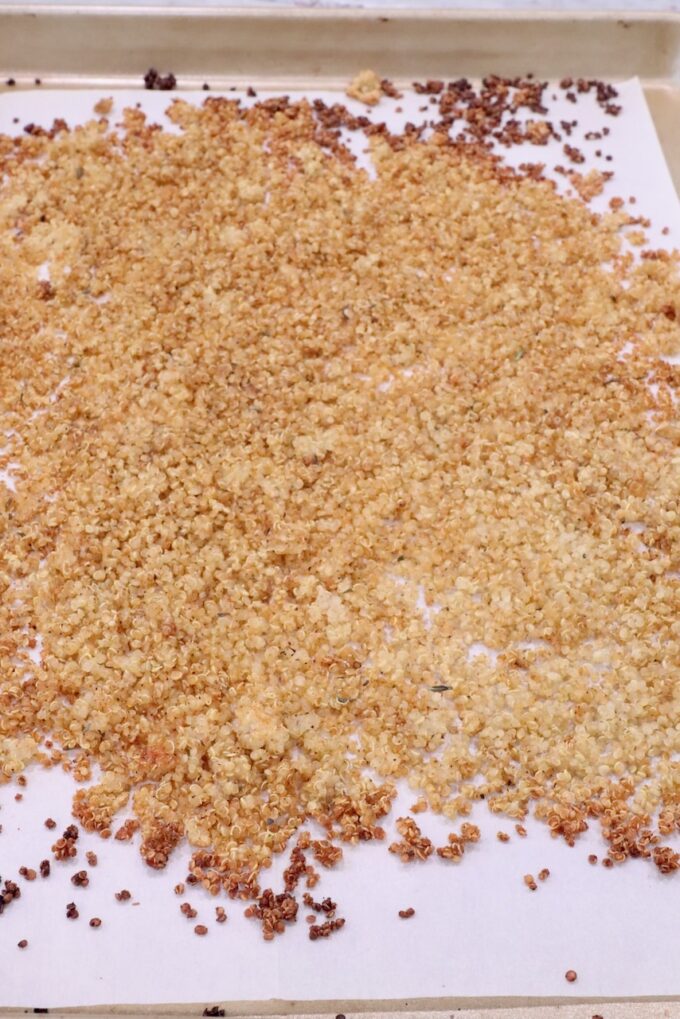 cooked crispy quinoa spread out on a parchment-lined baking sheet