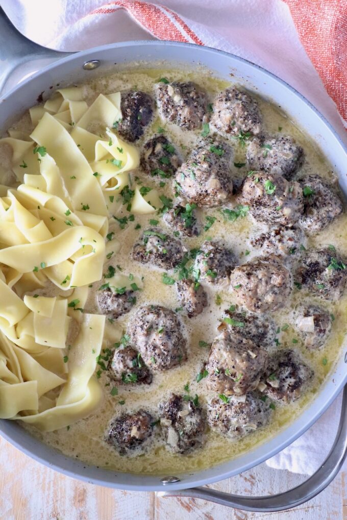 meatballs au poivre in a skillet with pappardelle pasta noodles