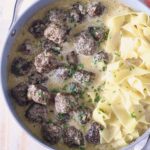 meatballs au poivre in a skillet with cooked egg noodles
