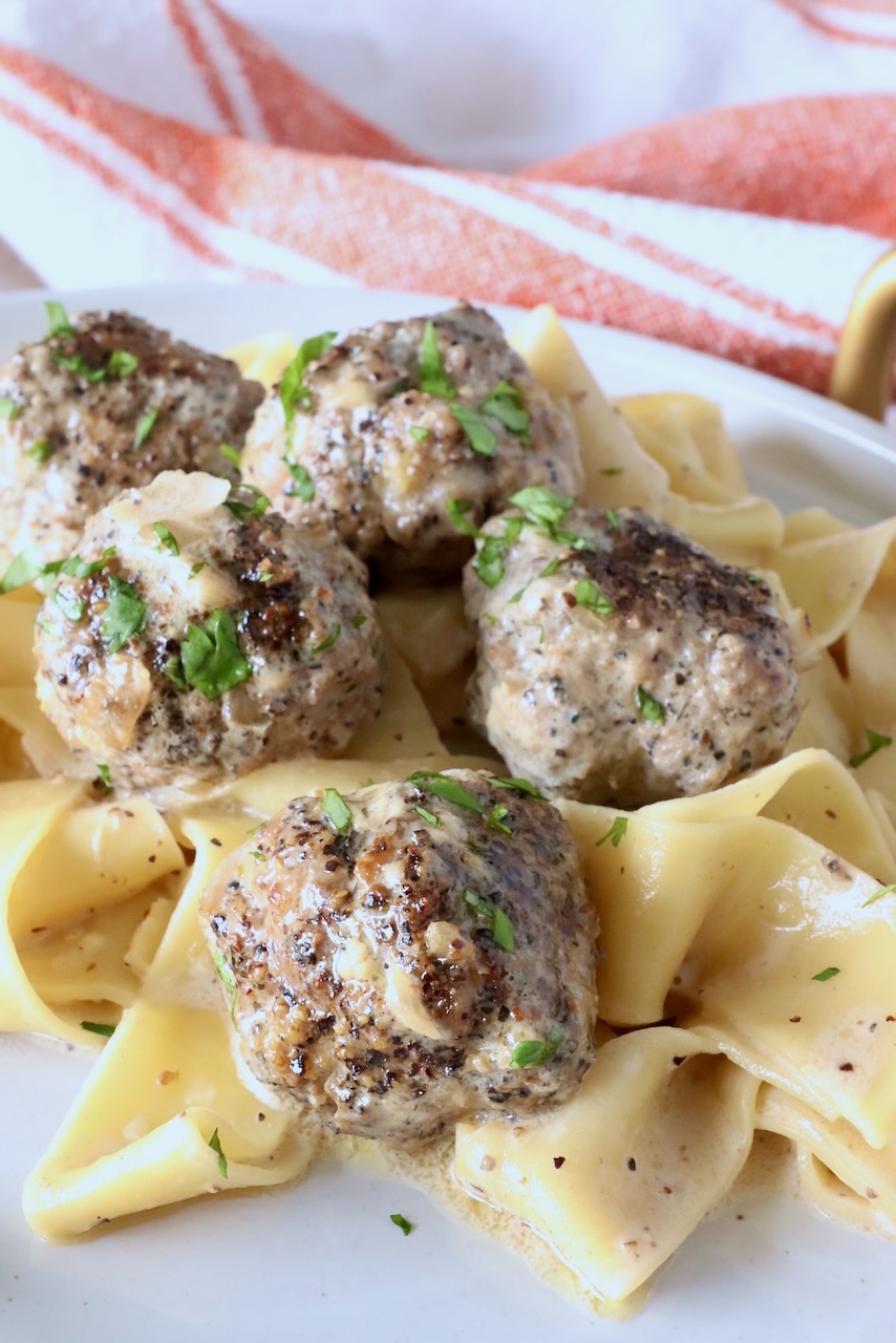 meatballs au poivre on top of pappardelle pasta on a plate