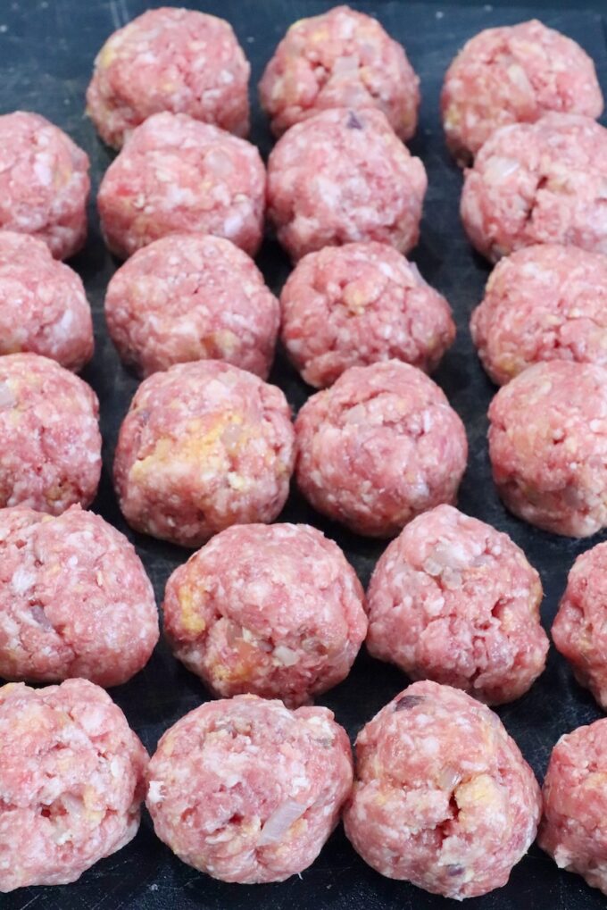 raw meatballs on a dark cutting board
